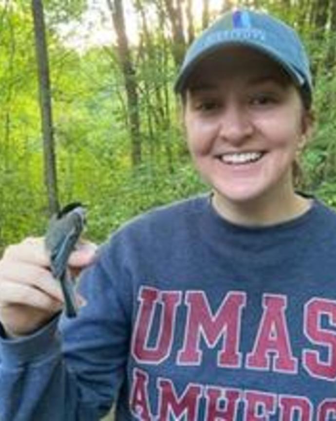 Isobel Smith holding small bird on finger in the woods